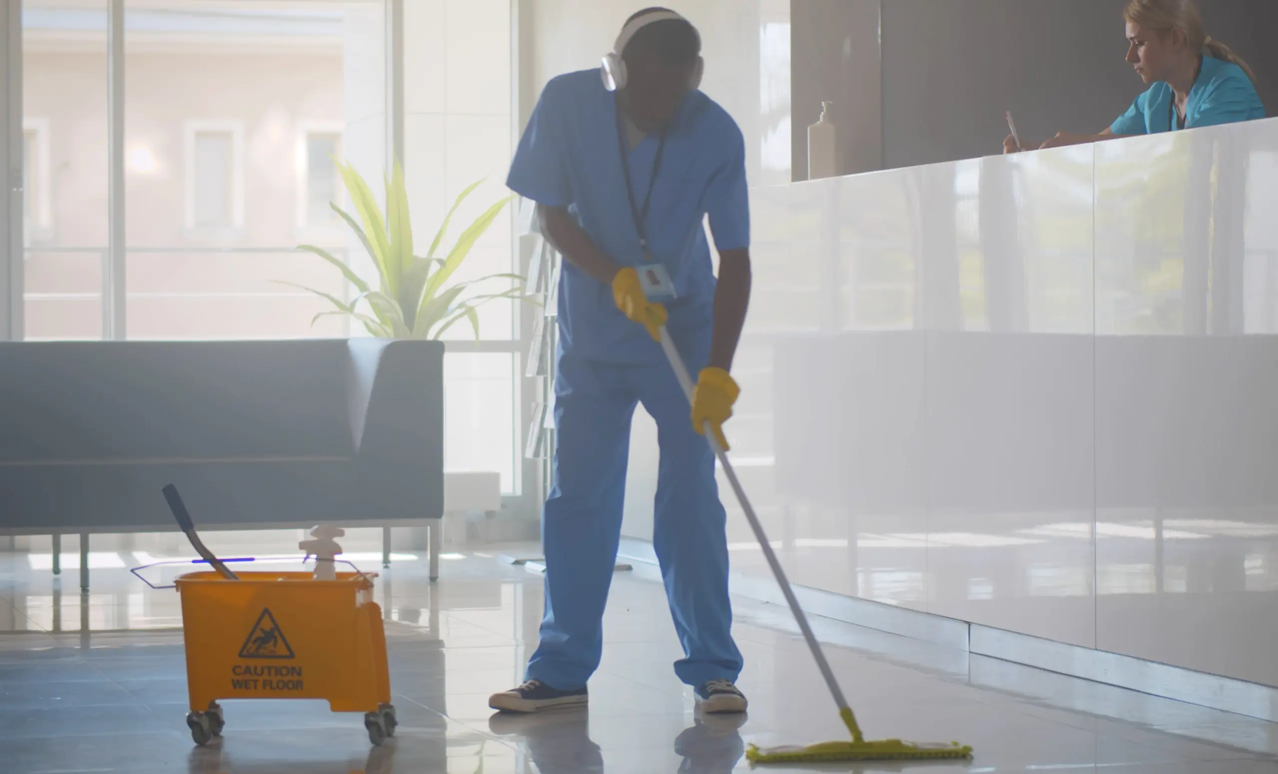 Person in blue scrubs mopping floor